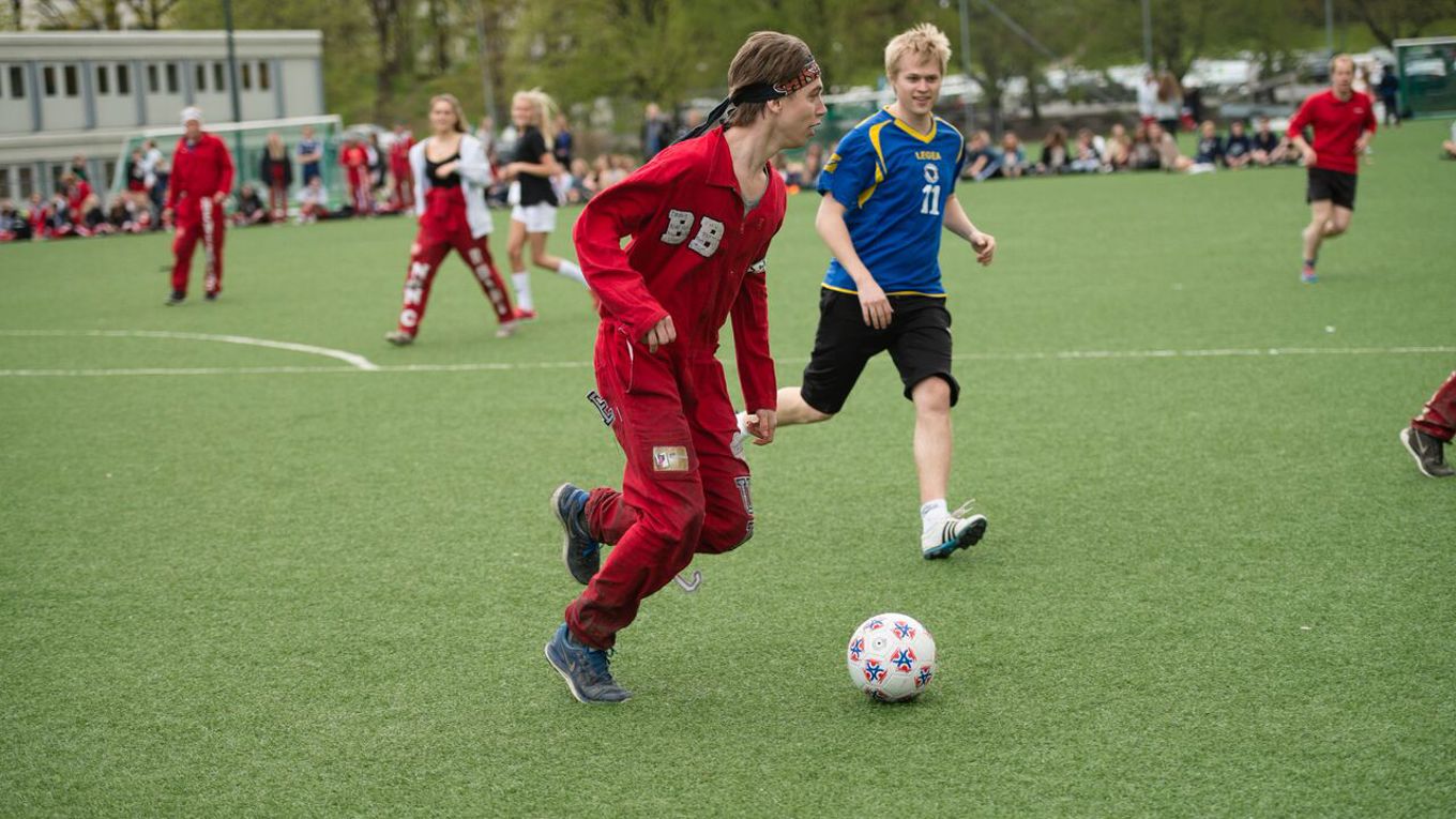 Russ og lærer på fotballbane. Fotballkamp mellom russen og lærerne er en tradisjon.
