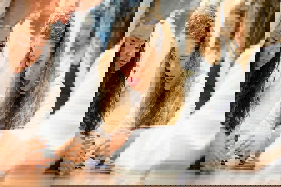 Engasjert jente gjør kjemiforsøk sammen med medelever i hvite frakker på kjemisalen.