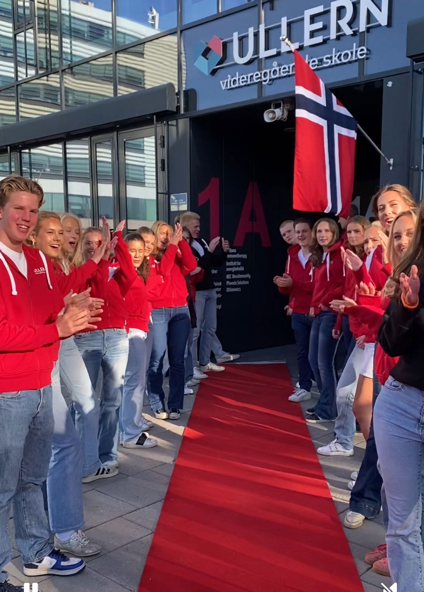 en gruppe mennesker som står på en rød løper med et flagg