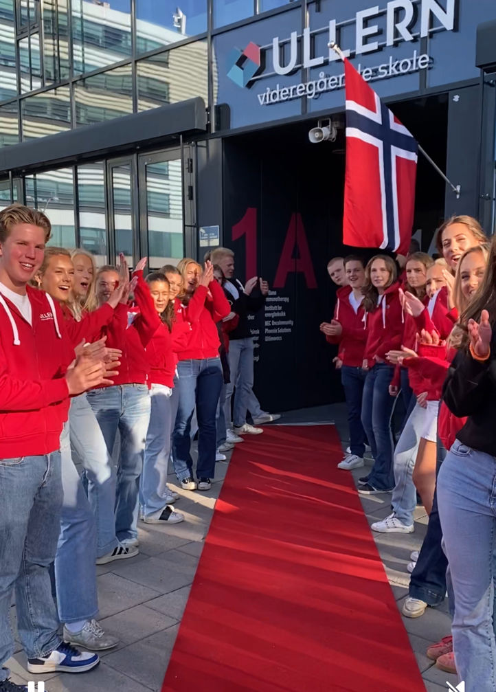 en gruppe mennesker som står på en rød løper med et flagg