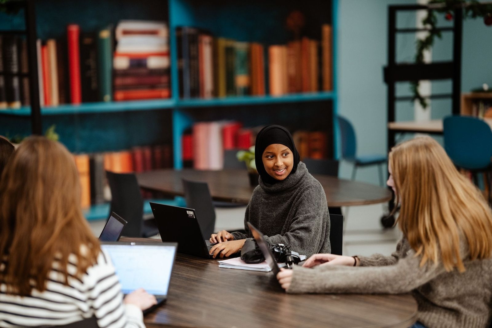 en gruppe personr som sitter ved et bord med bærbare datamaskiner
